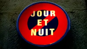 A lit up french sign that says "Jour et Nuit" with a red strikethrough